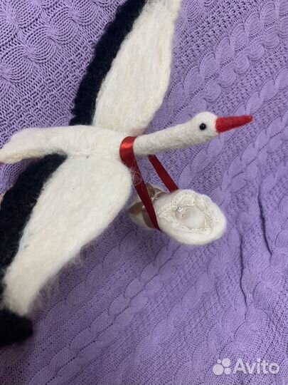 Аист с младенцем на красной ленте