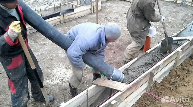 рабочие заливают бетон в опалубку фундамента